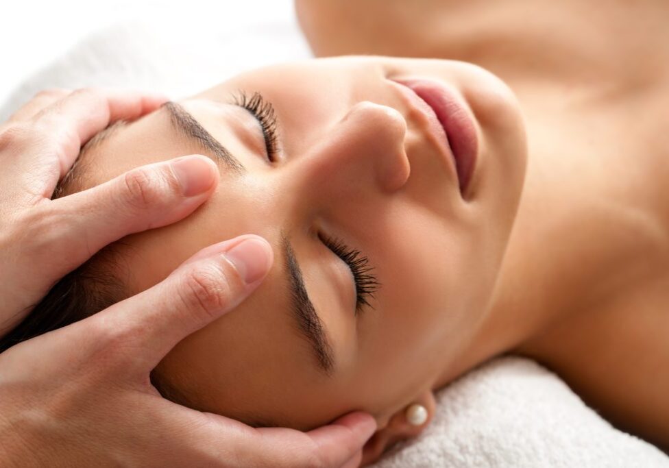 Close up head shot  of Woman having curative facial massage. Therapist applying pressure with thumbs on forehead.